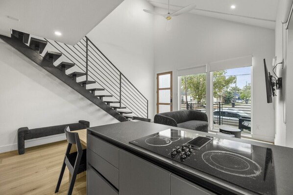 A modern kitchen with a black countertop, a built-in stove, and a black chair.