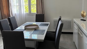 A dining area with a table set for six, chairs, a hanging light fixture, and a window with curtains. - Quiet house with garden (Alès)