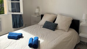 A bedroom with a bed, pillows, a nightstand, a lamp, and a window with curtains. - Quiet house with garden (Alès)