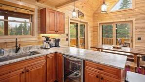 Cocina de cabaña de madera con encimeras de granito, gabinetes de madera y lavavajillas integrado.
