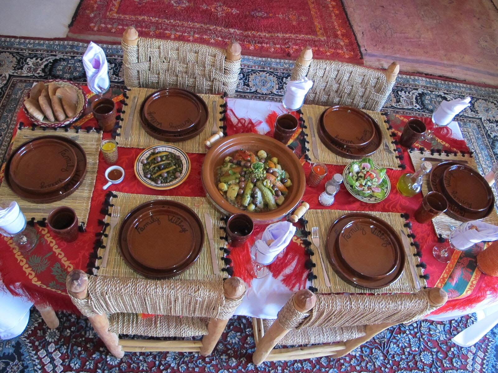 Una disposición tradicional marroquí para servir comida, con una mesa de fibras tejidas, platos marrones y un plato central de verduras.