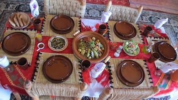 Una disposición tradicional marroquí para servir comida, con una mesa de fibras tejidas, platos marrones y un plato central de verduras.