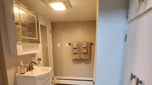A bathroom with a toilet, sink, mirror, towel rack, and a cabinet. - Spacious Apartment in Horseheads, NY (Horseheads)