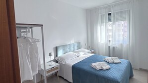 A hotel room with a bed, a wardrobe, a nightstand, and a window with curtains.