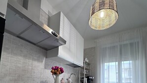 A modern kitchen with white cabinetry, a built-in oven, and a pendant light.