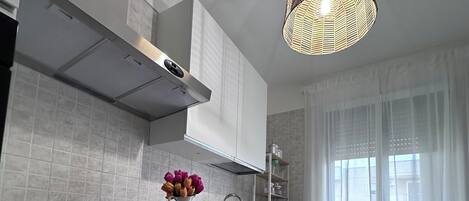 A modern kitchen with white cabinetry, a built-in oven, and a pendant light.