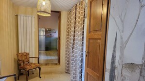 A hallway with a patterned curtain, a wooden door, and a chair. - Renovated farmhouse with swimming pool and 3ha garden (Limeuil)