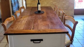 A wooden dining table with six chairs, a bottle of wine, and a small decorative item on the table. - Renovated farmhouse with swimming pool and 3ha garden (Limeuil)