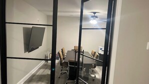 A conference room with a glass partition, a ceiling fan, and a table with chairs.