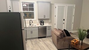 A modern kitchen with white cabinets, a stainless steel refrigerator, and a coffee maker on the counter.