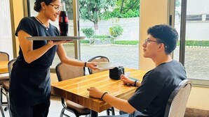 A person seated at a wooden table with a tray of food and a bottle of Coca-Cola. - Hotel California Pacific Palm (Escuintla)