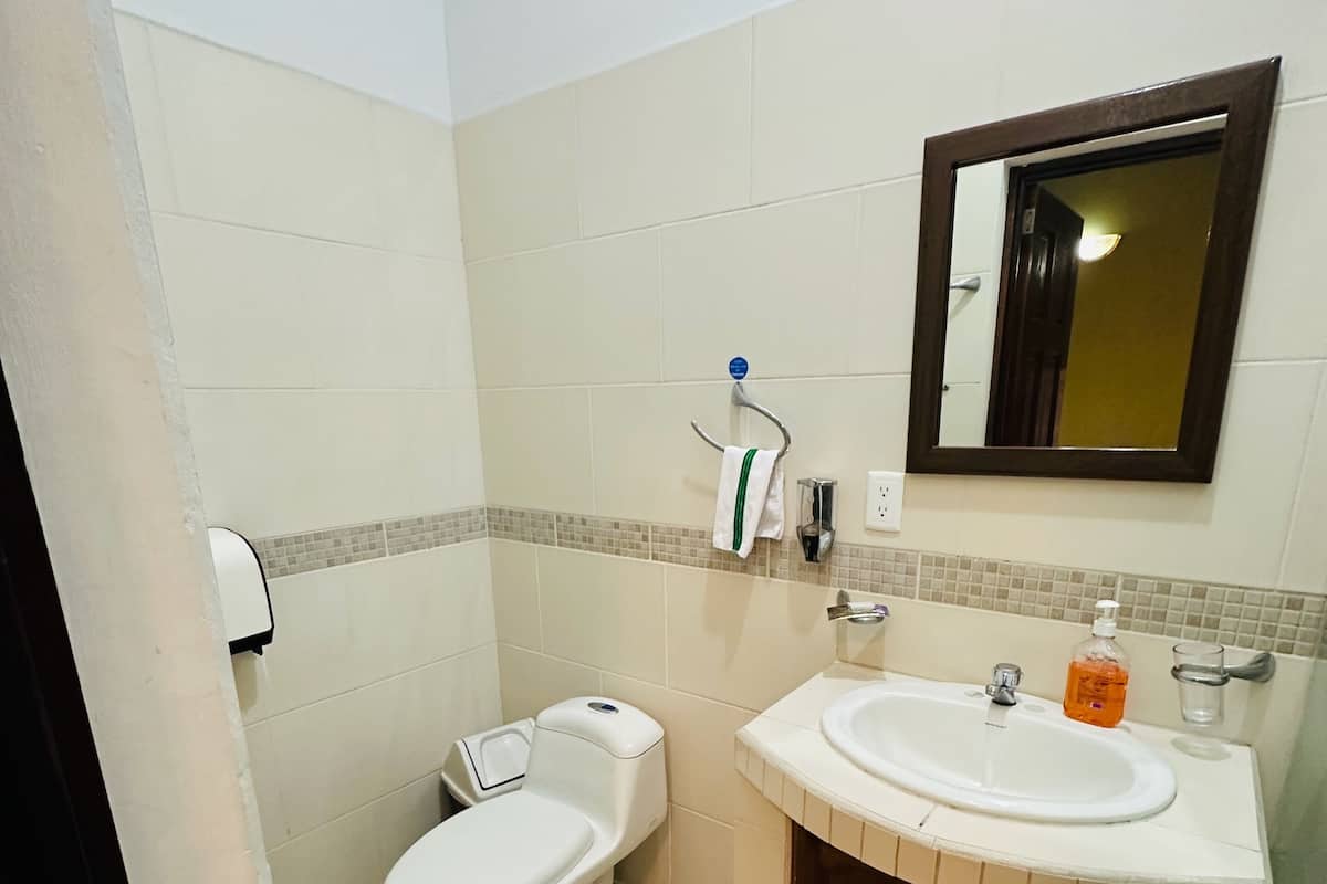 Ein Badezimmer mit Toilette, Waschbecken, Spiegel und Fliesenboden.