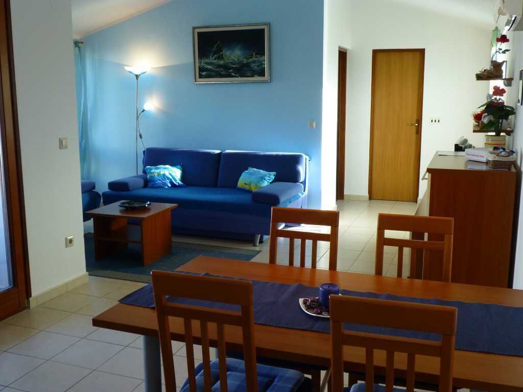 A living room with a blue sofa, wooden dining table, and chairs.