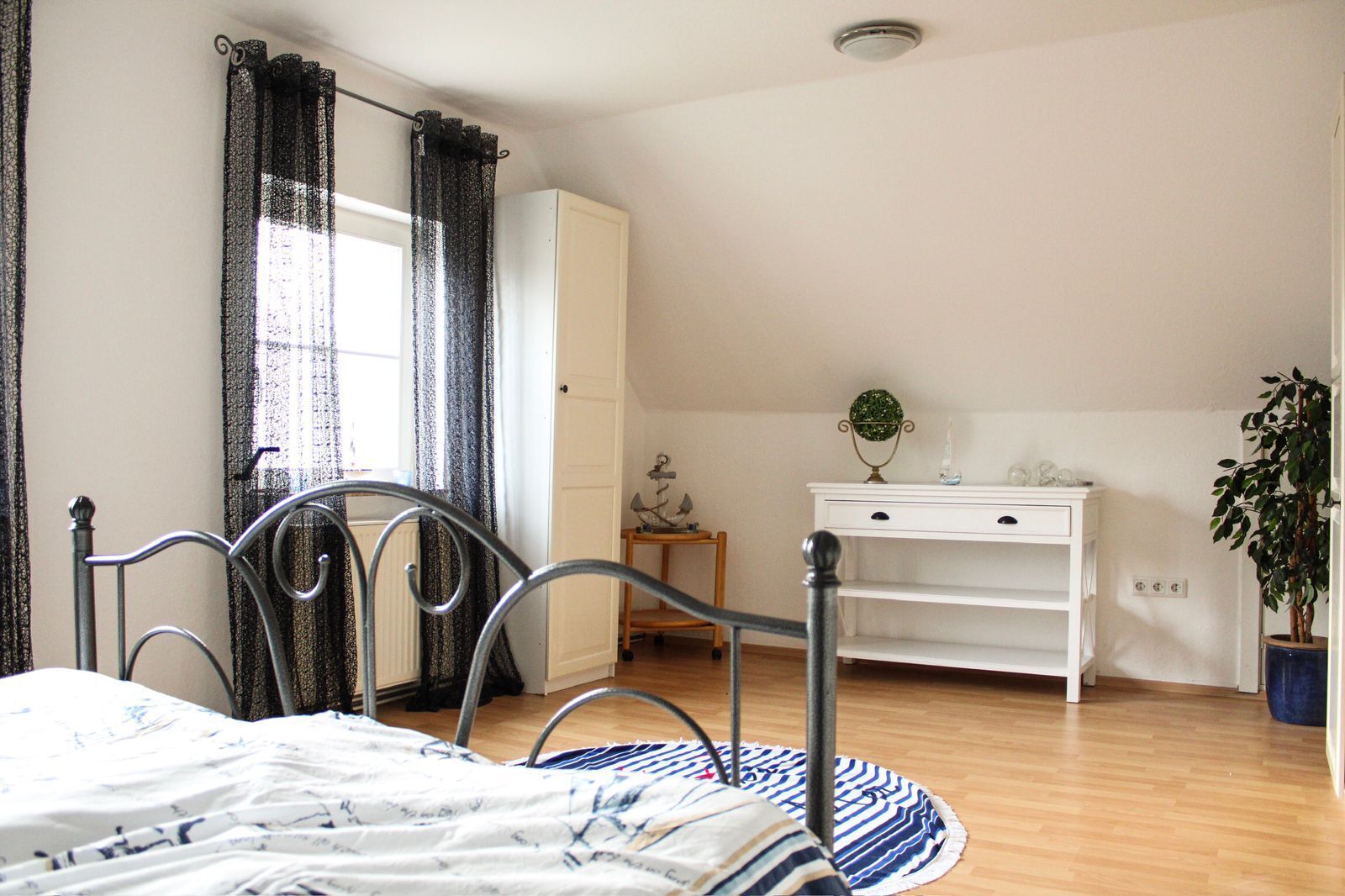 Une chambre à coucher avec un lit, une commode, un bureau et une plante en pot.