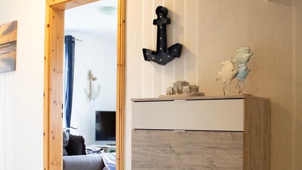 A room with a wooden wardrobe, a bed, and a television in the background. - Cast off - maritime vacation home in the countryside (Krummhörn)