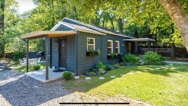 A modern house with a covered porch, a well-maintained lawn, and a variety of plants. - Historic Uptown Retreat in Hot Springs, Arkansas (Hot Springs)