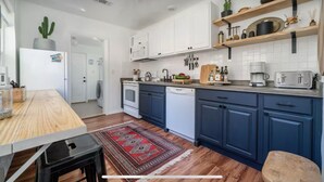 A modern kitchen with white cabinets, a wooden countertop, and a red patterned rug. - Historic Uptown Retreat in Hot Springs, Arkansas (Hot Springs)