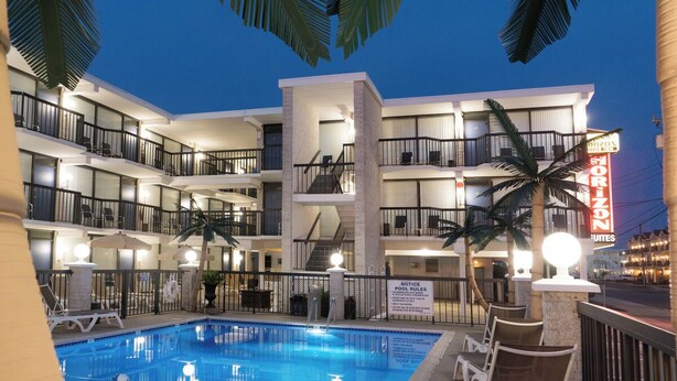 Un hotel de varios pisos con piscina, balcones y un letrero de neón.