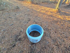 A blue bucket filled with soil on a forest floor.