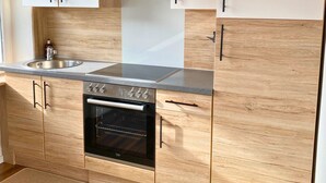 Eine moderne Küche mit Holzschränken, einer Edelstahlspüle und einem eingebauten Backofen.