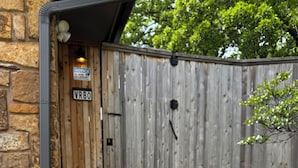 Une façade en pierre avec une porte en bois, un tuyau en métal et une clôture en bois portant le numéro de la maison.