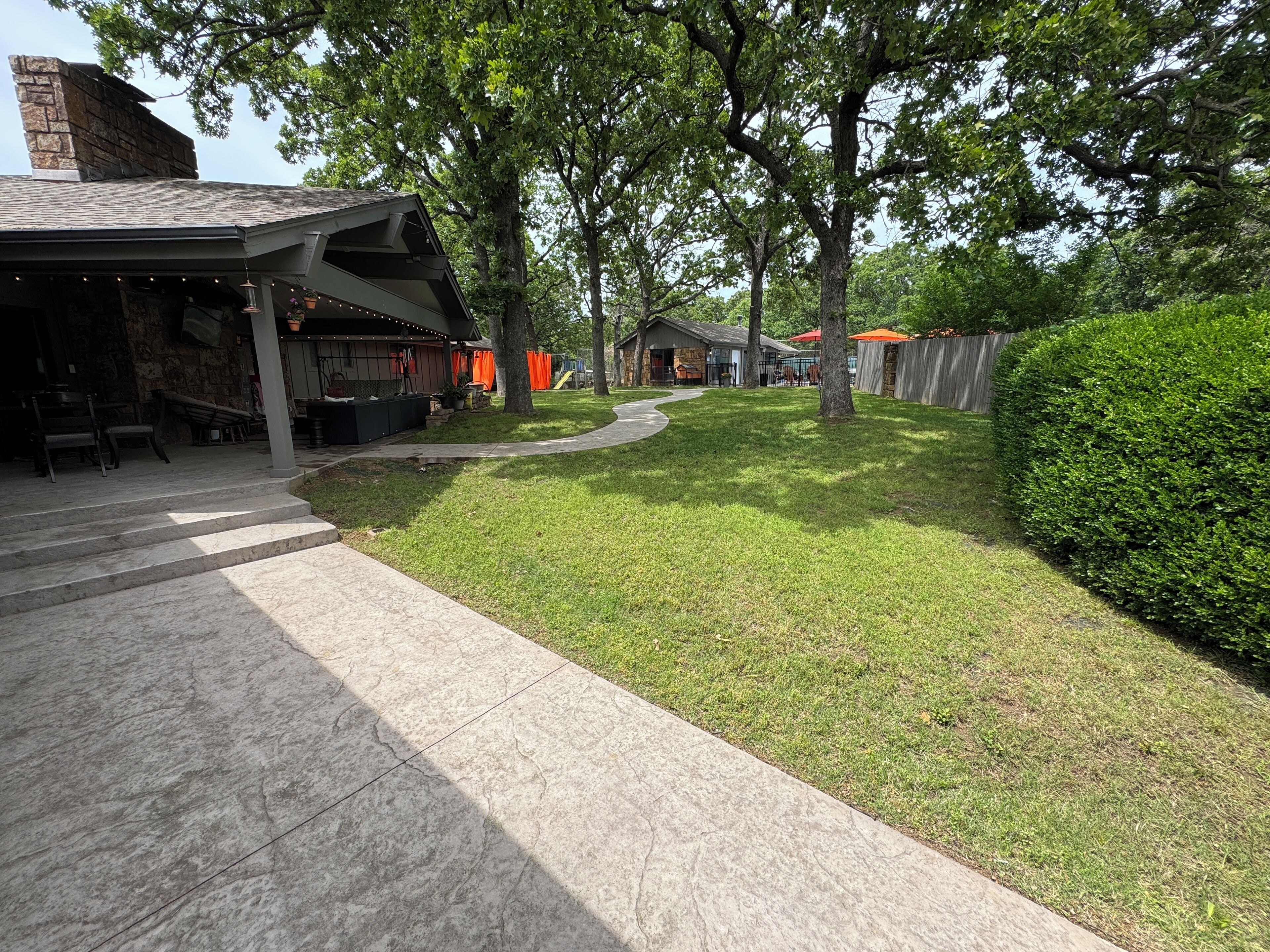 Un patio con mobiliario exterior y un camino de piedra que lleva a un edificio con techo inclinado.
