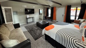 Une chambre d’hôtel moderne équipée d’un grand lit, d’un canapé, d’une télévision et d’une petite kitchenette.