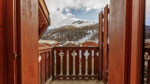 Ein Holzbalkon mit Blick auf schneebedeckte Berge und Gebäude.