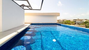 A rooftop swimming pool with a clear blue water feature, surrounded by a white wall and a metal structure. - King Studio w/ Balcony, Rooftop Pool | Aldea Zama (Tulum)