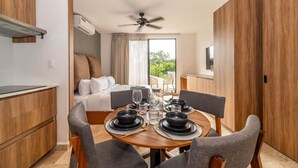 A modern hotel room with a dining area, a bed, and a balcony with a view. - King Studio w/ Balcony, Rooftop Pool | Aldea Zama (Tulum)