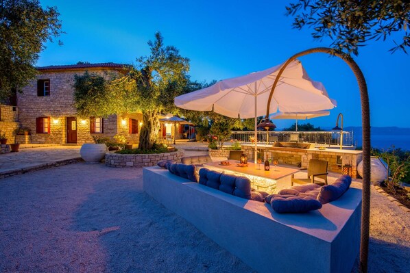 A stone building with a patio area featuring outdoor seating and a large umbrella.