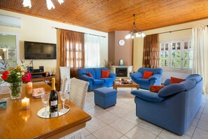 Un salon chaleureux avec des canapés bleus, un plafond en bois, une cheminée et un téléviseur fixé au mur.