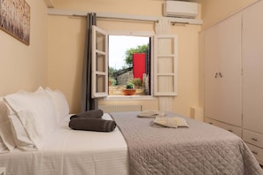 Un dormitorio con cama, ventana con cortinas, radiador y armario.