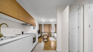 A modern kitchen with white cabinetry, a gold faucet, and a dining area with a white table and chairs.