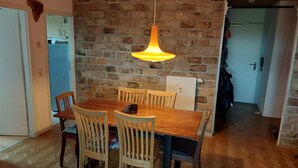 Un coin repas avec un mur en briques, une table en bois et des chaises.
