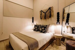 A bedroom with a bed, bedside tables, a hanging light fixture, and a mirror. - Naiik Jungle Retreat Private Pool Beach Club (Tulum)