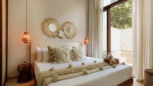 A bedroom with a large bed, two wall mirrors, a bedside lamp, and a view through a window.