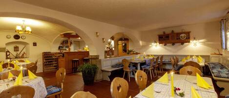 Un restaurante con sillas y mesas de madera, una zona de bar y un ambiente cálido y acogedor.