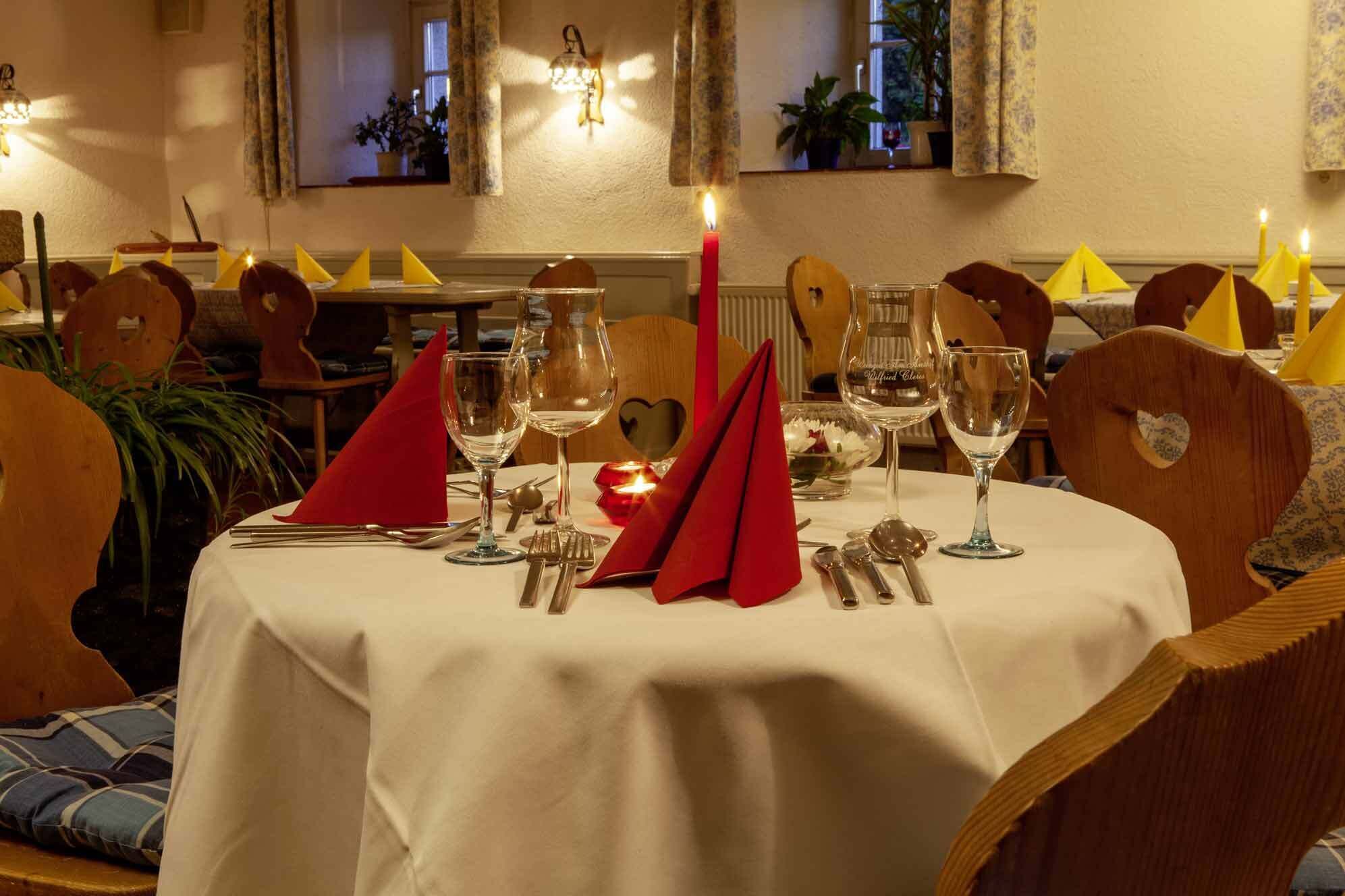 A dining table set with wine glasses, cutlery, and red napkins.