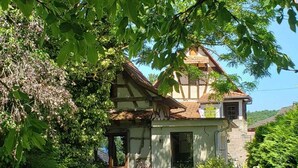 Une maison traditionnelle à colombages, dotée d’un jardin bien entretenu, d’une chaise pliante et d’une petite table.