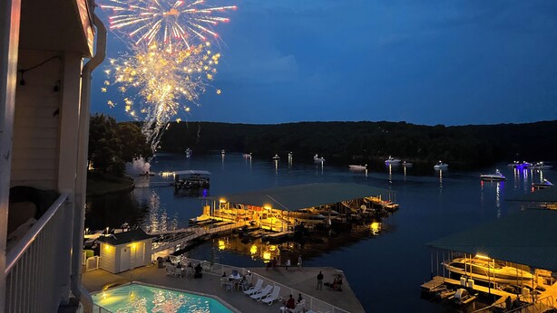 A waterfront view with boats docked, a docked boat, and a swimming pool.