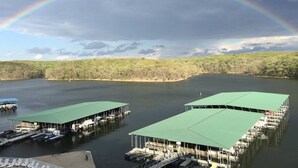 A lakeside dock with green-roofed structures, boats, and a forested shoreline.