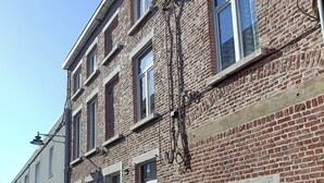 A brick building with multiple windows and a satellite dish. - Charming house Centre de Mons (Mons)
