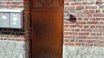 Een houten deur met een bakstenen muur, een brievenbus en een beveiligingsbox.