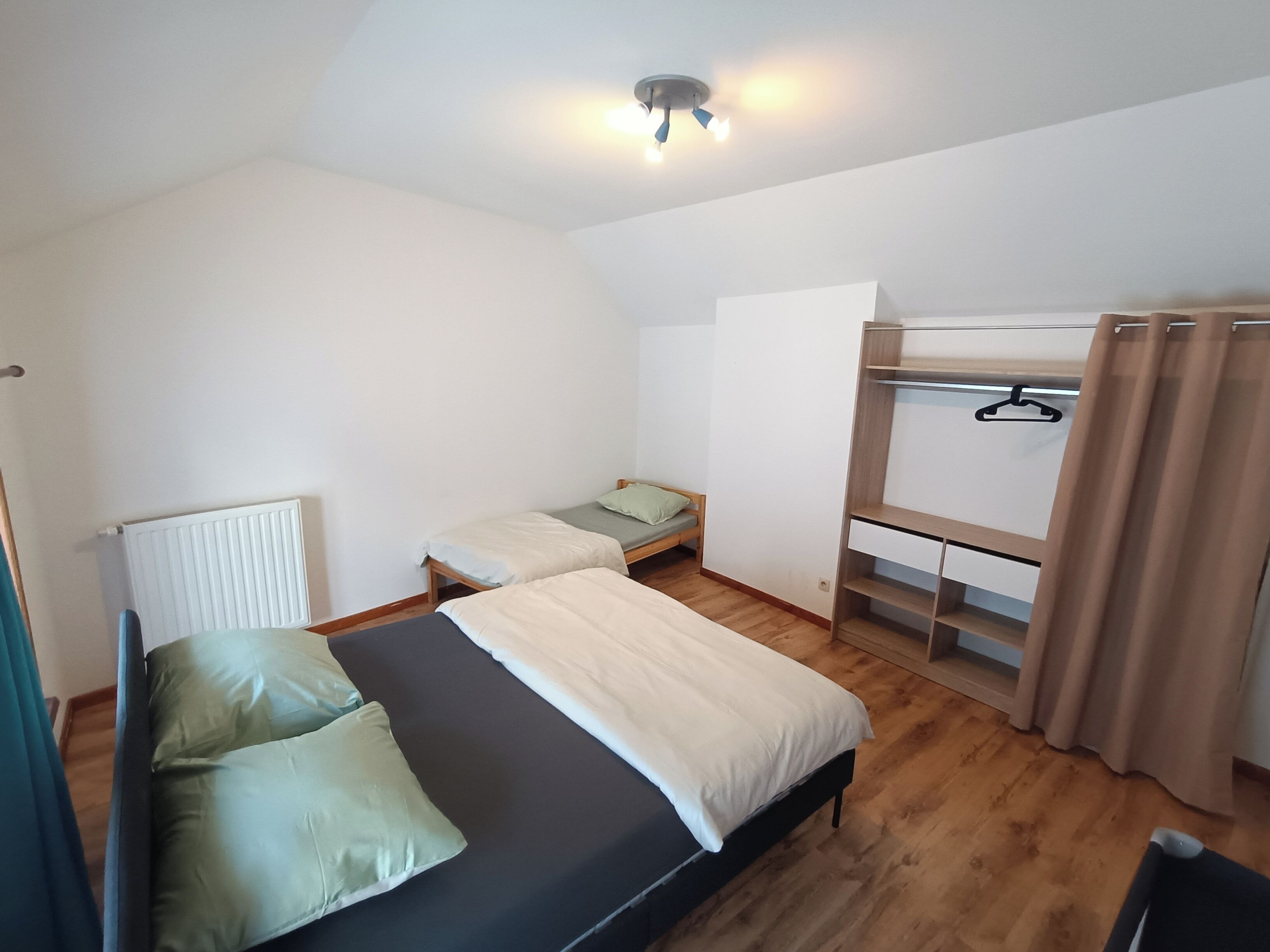 Une chambre de dortoir avec des lits superposés, un petit bureau et un radiateur.