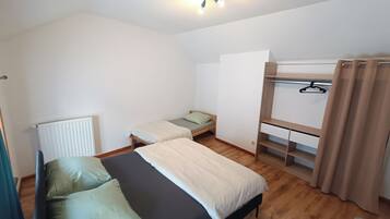 Une chambre de dortoir avec des lits superposés, un petit bureau et un radiateur.