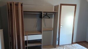 A bedroom with a bed, a wooden wardrobe, and a door. - Charming house Centre de Mons (Mons)