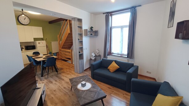 A modern living room with a sofa, coffee table, and dining area. - Charming house Centre de Mons (Mons)
