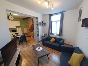 Een moderne woonkamer met een bank, salontafel en eethoek.