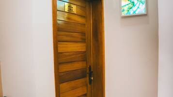 Une porte en bois avec une plaque indiquant le numéro de la chambre, un sol carrelé et un tableau encadré accroché au mur.